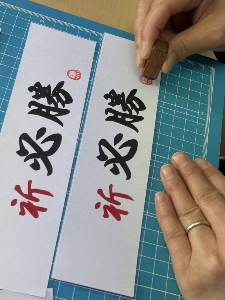 必勝シールに、当選祈願の意味を込めて、ダルマのはんこを1枚ずつ押している作業風景